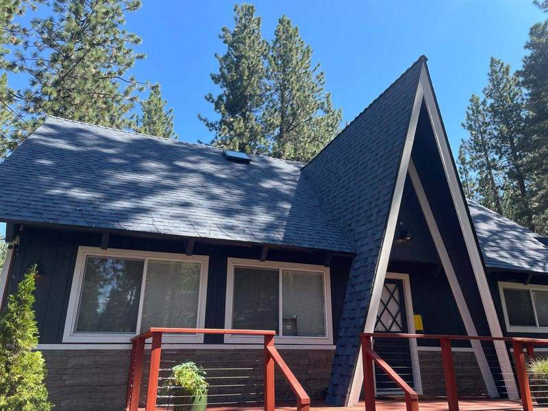 Dark A-frame cabin with a red deck and a new architectural shingle roof near South Lake Tahoe