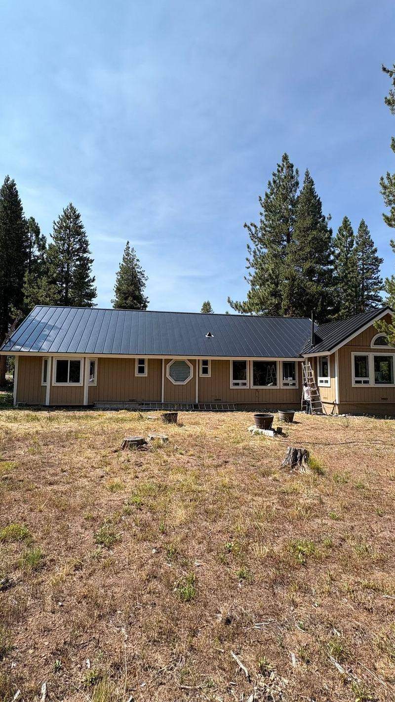 Dark metal roof on a single-story ranch-style home in South Lake Tahoe, pines behind