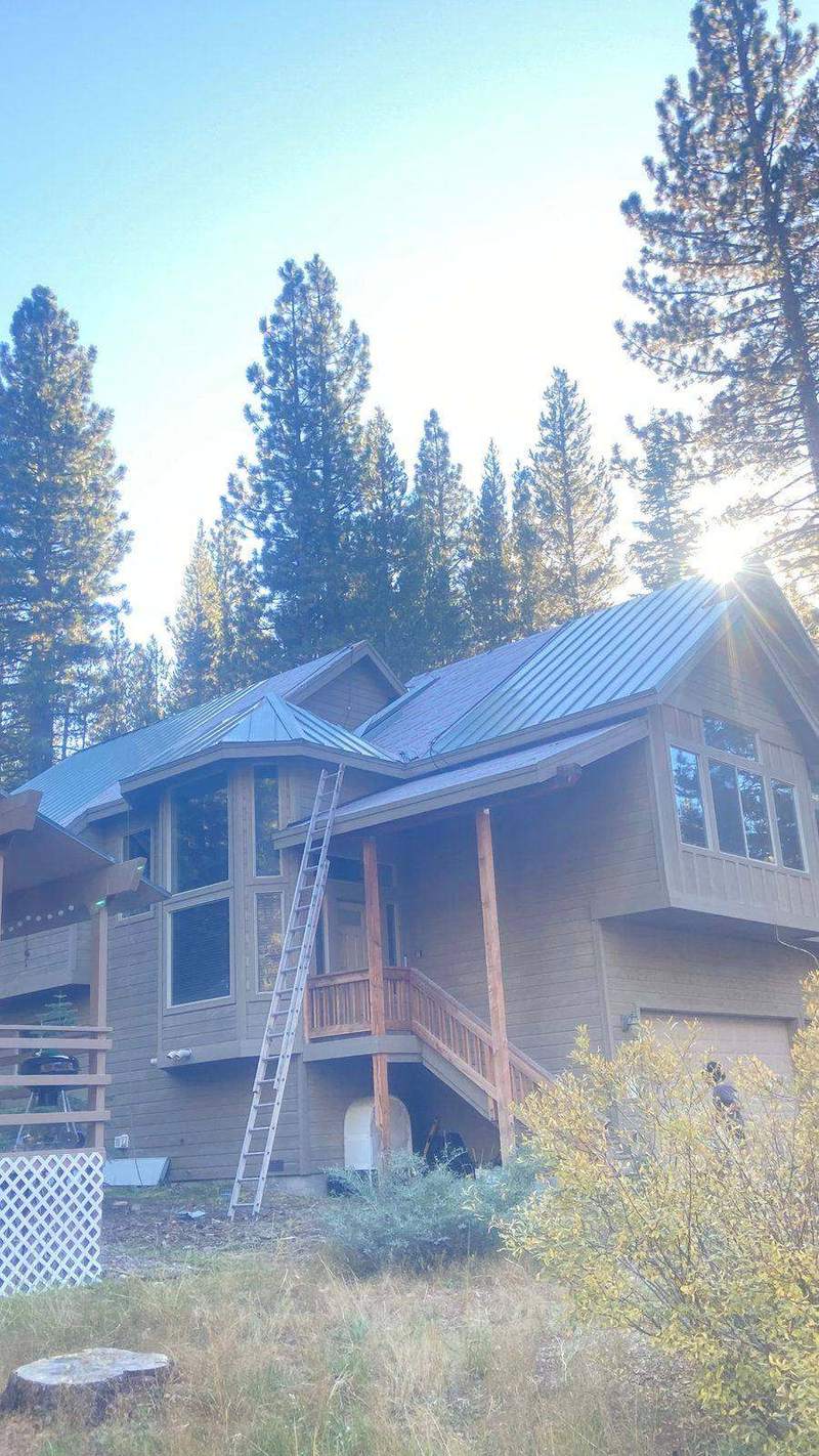 Grey standing seam metal roof on a two-story South Lake Tahoe home with sun coming through the pines