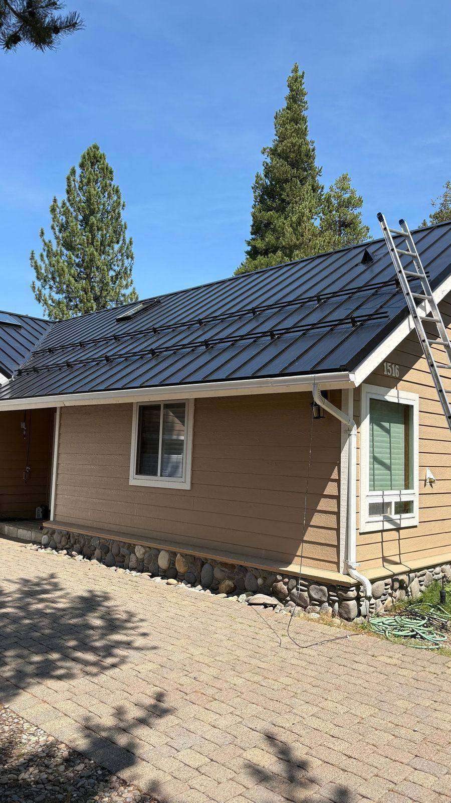 Dark standing seam metal roof on a tan South Lake Tahoe home with the crew's ladder at the eave